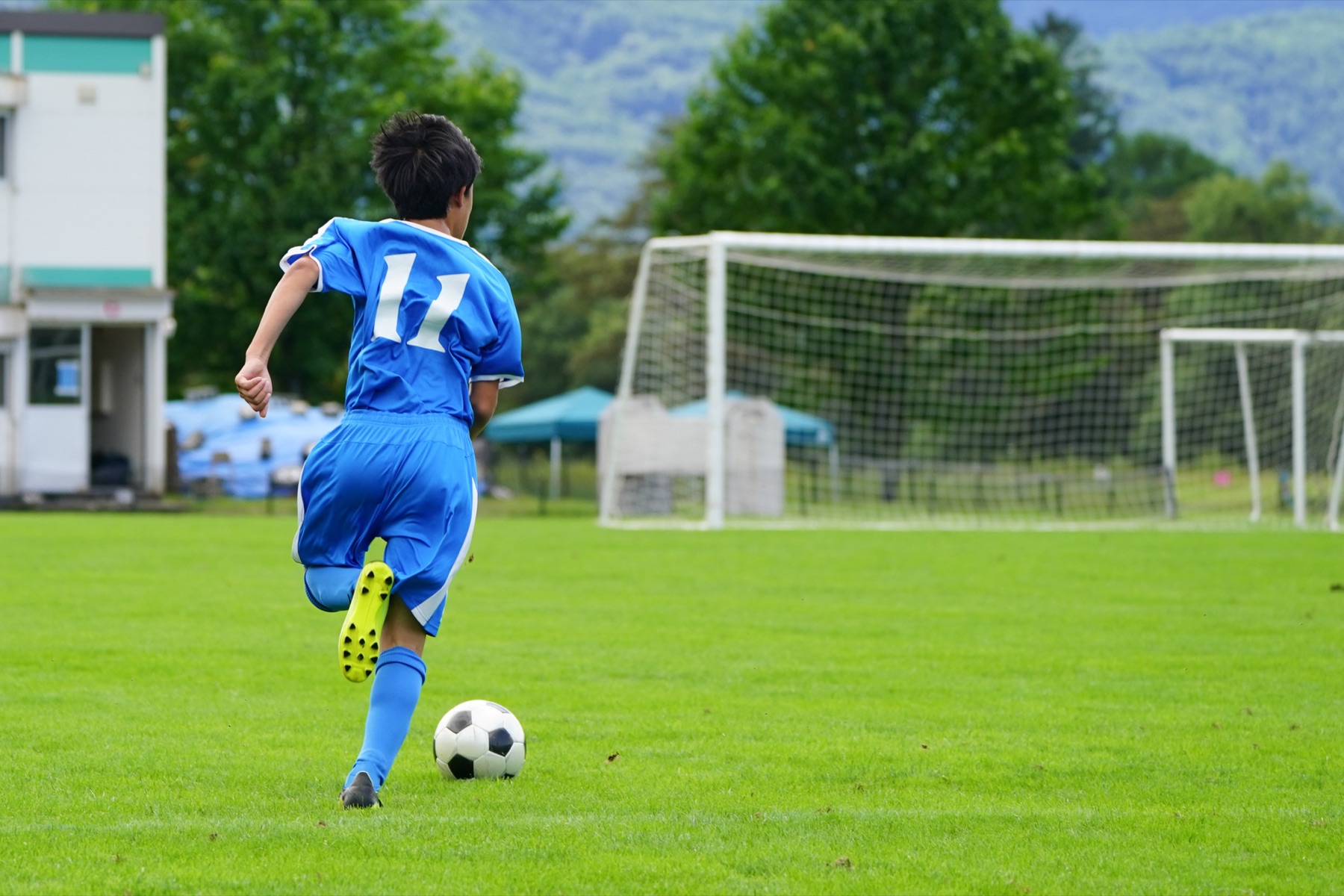 ゴールへ向かってドリブルする中高生サッカー選手